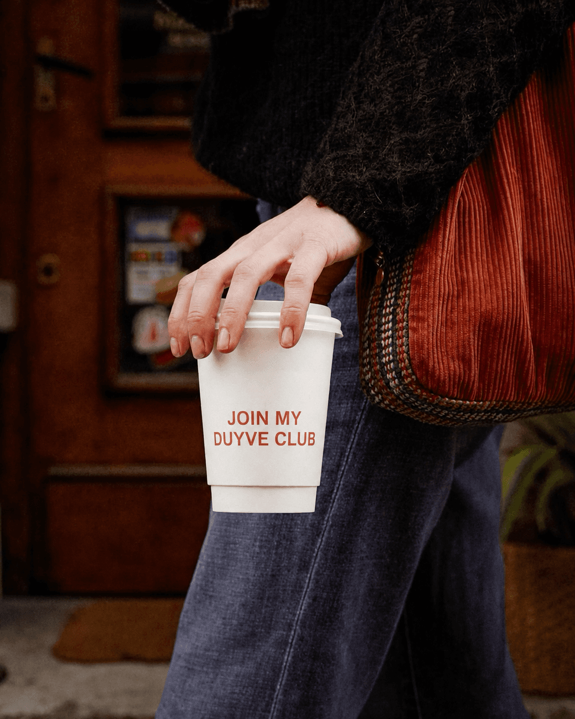 Person holding a coffee cup inviting people to join a Duyve club